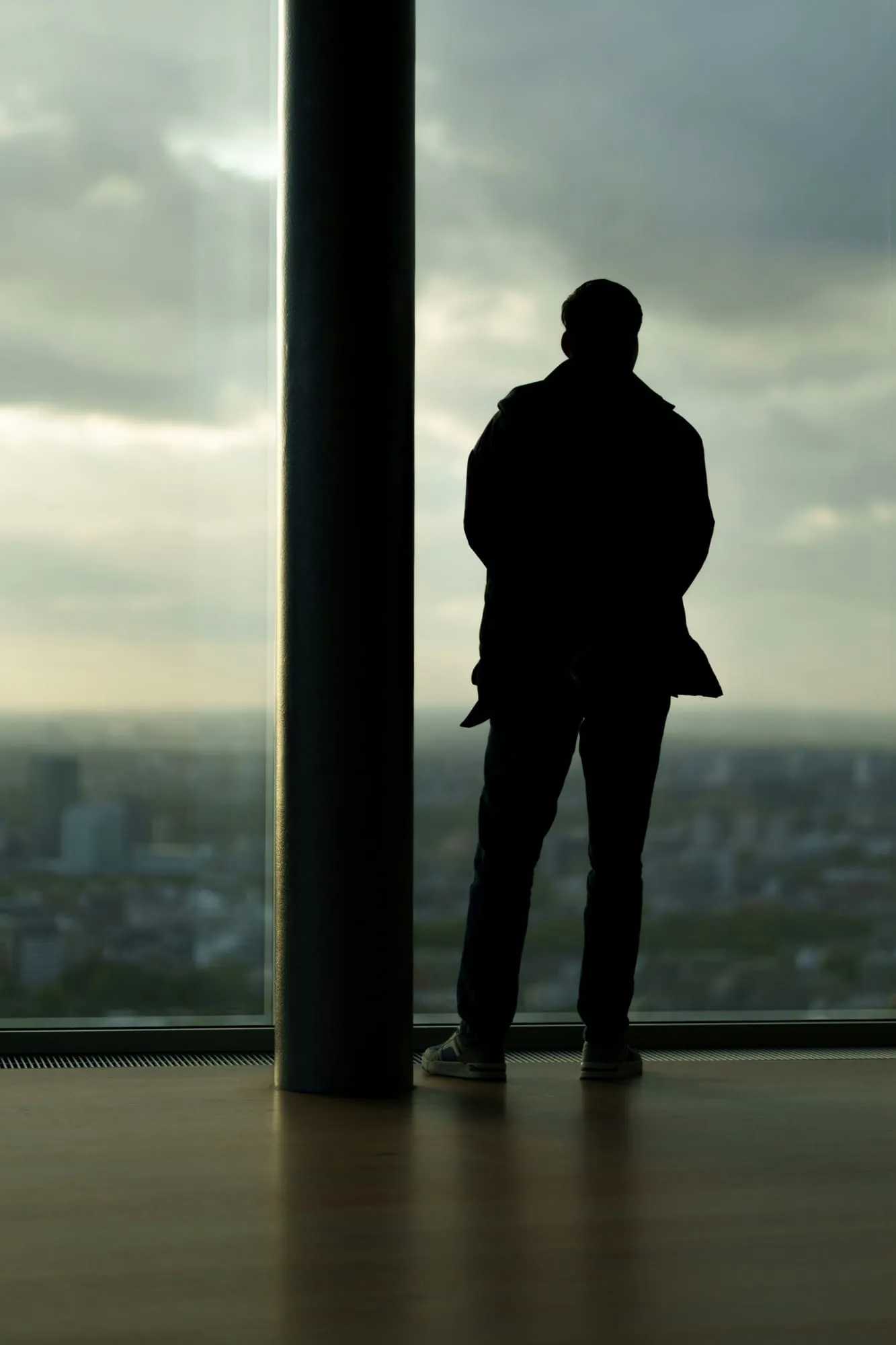 Silhouette eines Mannes am Fenster mit Blick auf die Stadt